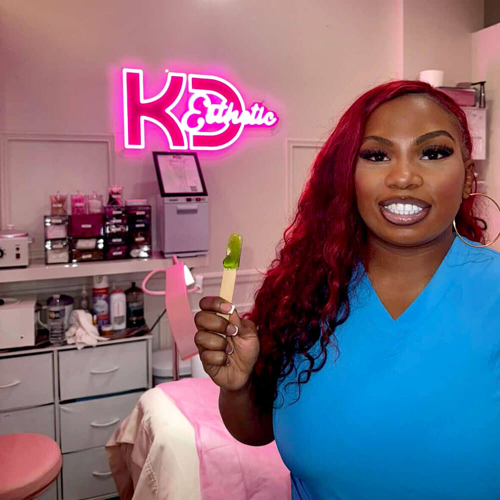 Neon sign with 'KD Esthetic' on a wall in a clinical setting.