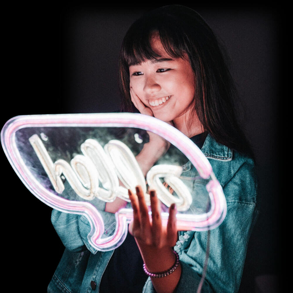 Lady holding a neon sign with the word 'hello' against a dark background